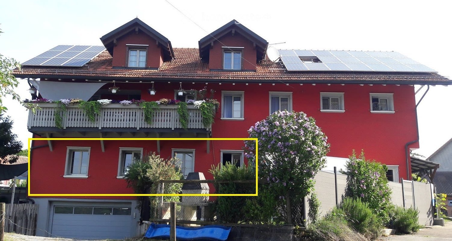 Red two-story house with solar panels, balcony, and garage.