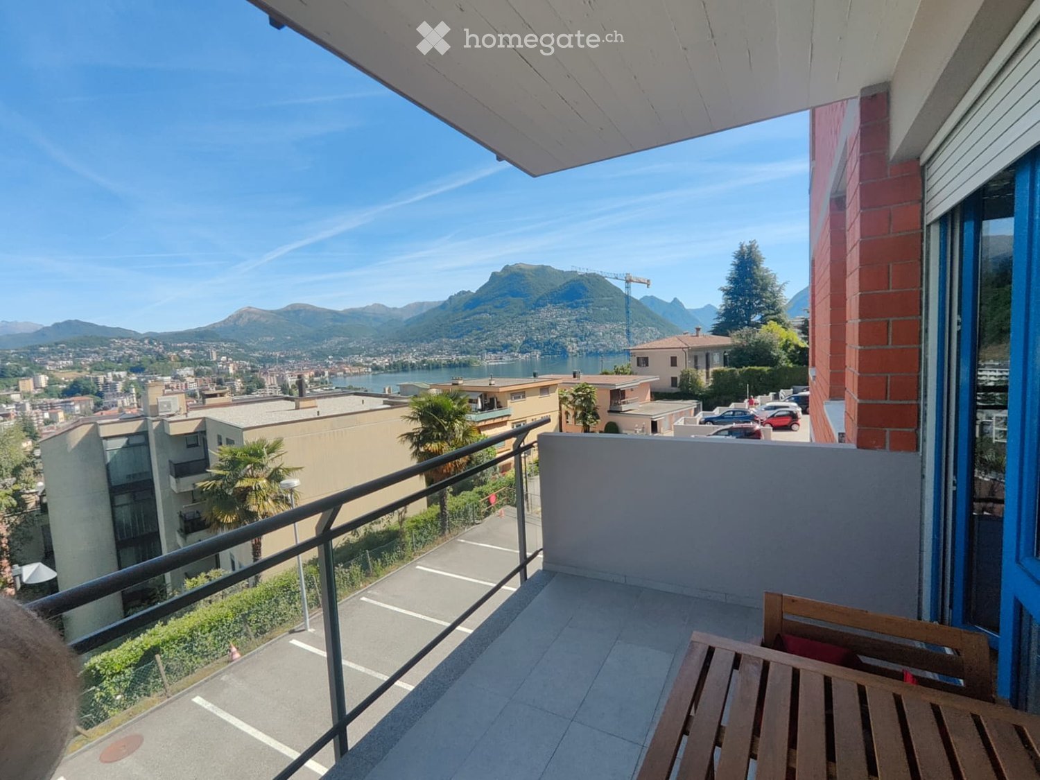 Balcony with a wooden bench, overlooking a scenic lake and mountain view.