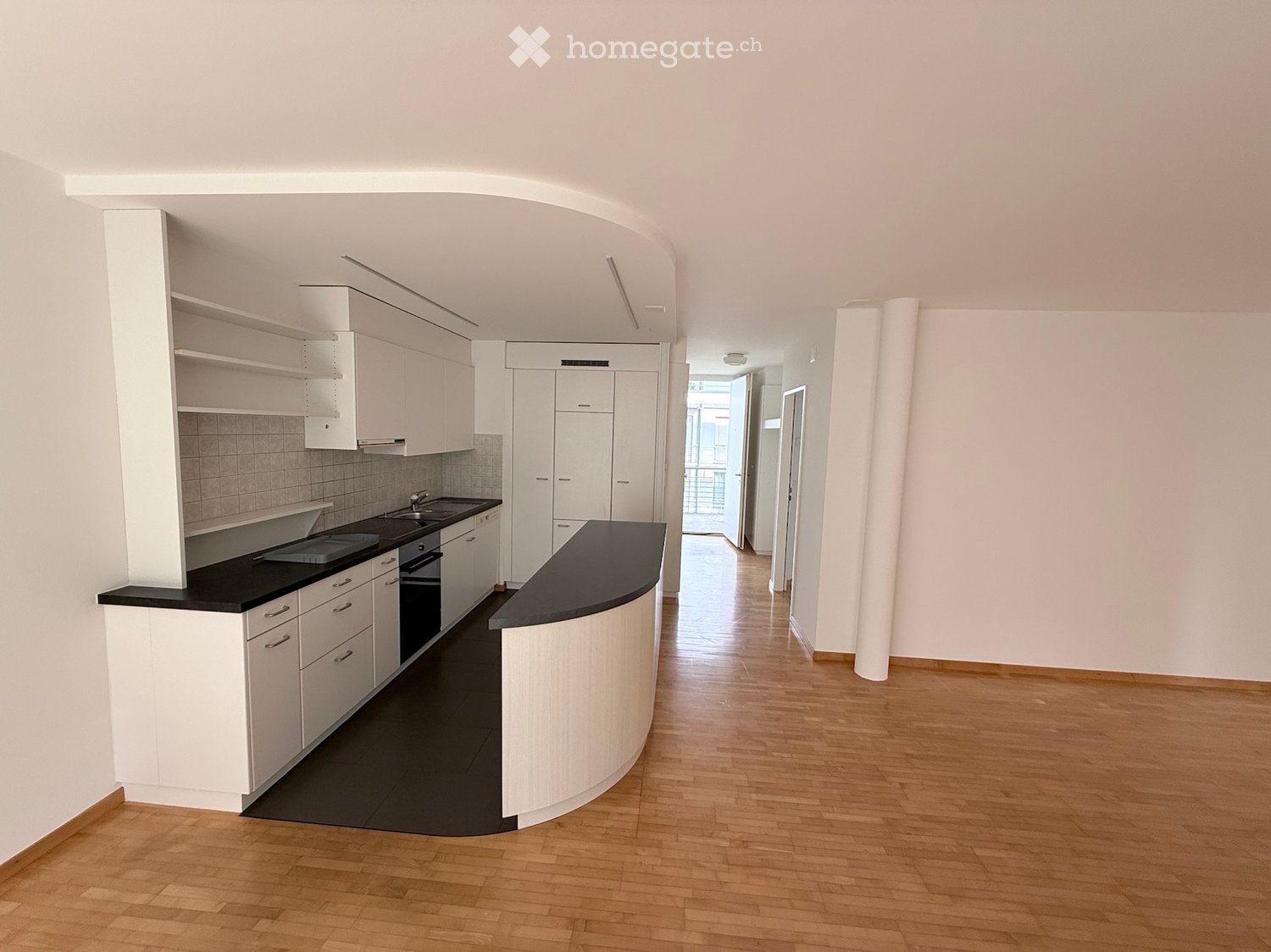 Modern kitchen with white cabinets, black countertops, and a central island. Features a sink, faucet, and built-in oven.