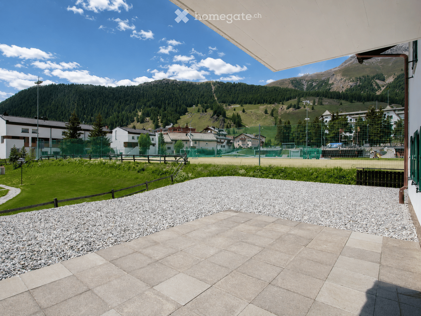 Balcony with stone tiles, gravel area, and scenic mountain view in the background.