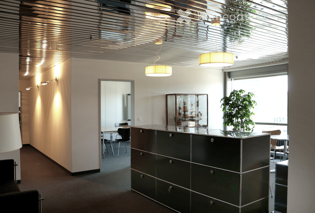 Modern office space with sleek black cabinetry, pendant lights, a potted plant, and a display case with a model ship.