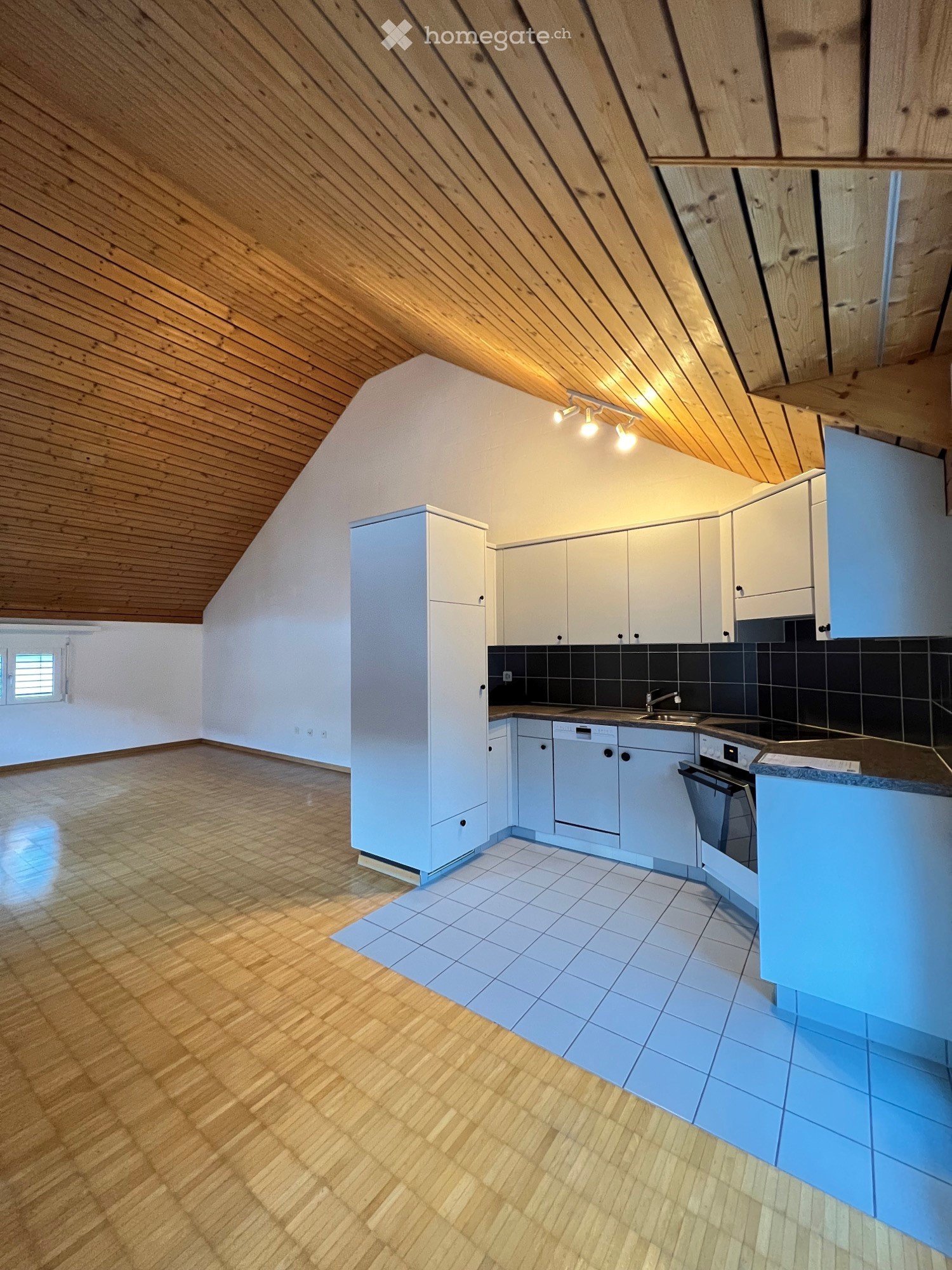 Modern kitchen with white cabinets, wooden ceiling, and tiled floor. Features a sink, faucet, oven, and dishwasher.