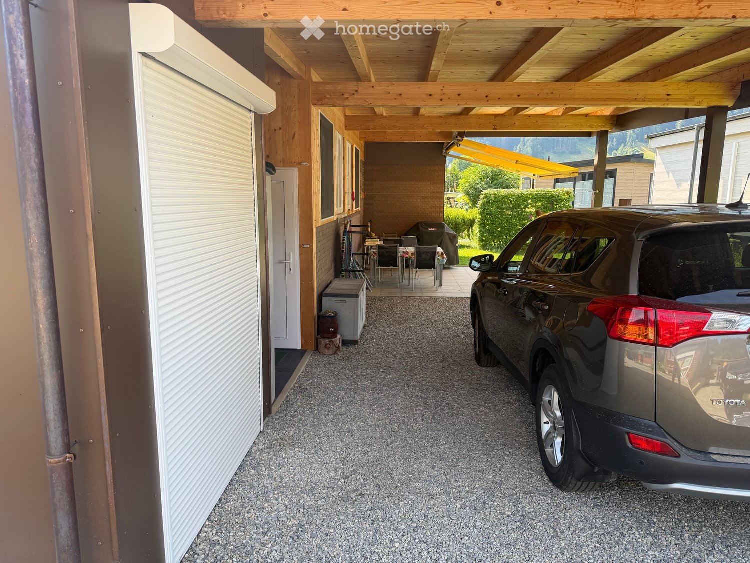{"type": "Garage", "objects": [], "description": "Gravel driveway with a parked SUV, covered outdoor seating area with tables and chairs, and a covered entryway.", "visible_features": ["Garage"], "localized_descriptions": {"EN": "Gravel driveway with a pa