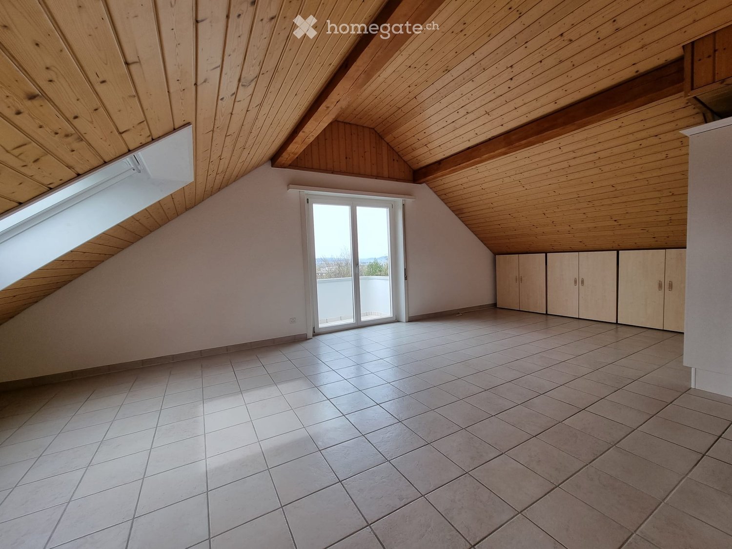empty room with glass door to balcony, wooden ceiling, tile floor, cabinets on wall