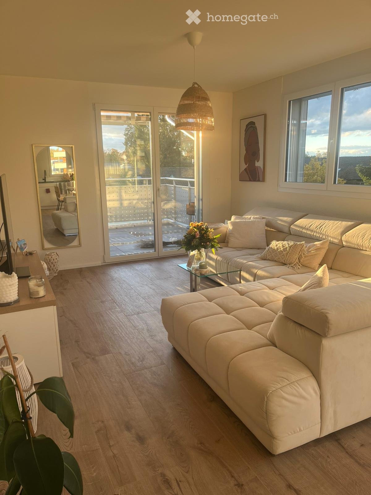 L-shaped white sofa, glass coffee table, mirror, framed picture, sliding doors, balcony