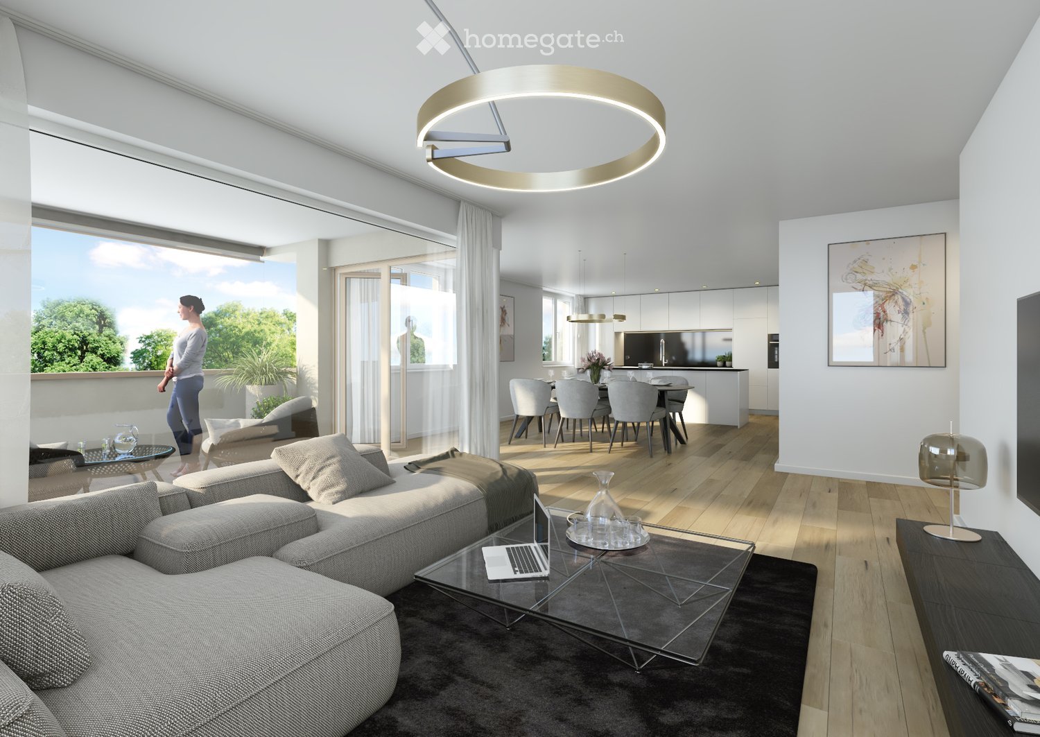 Modern living and dining area with a grey sectional sofa, glass coffee table, laptop, side table, dining table with chairs, kitchen area, and large windows offering a view of greenery.