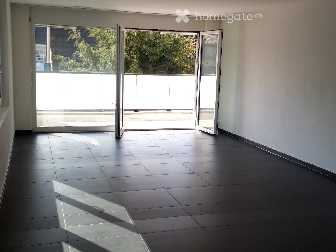 Empty room with dark tiled floor and large sliding glass doors leading to a balcony area.