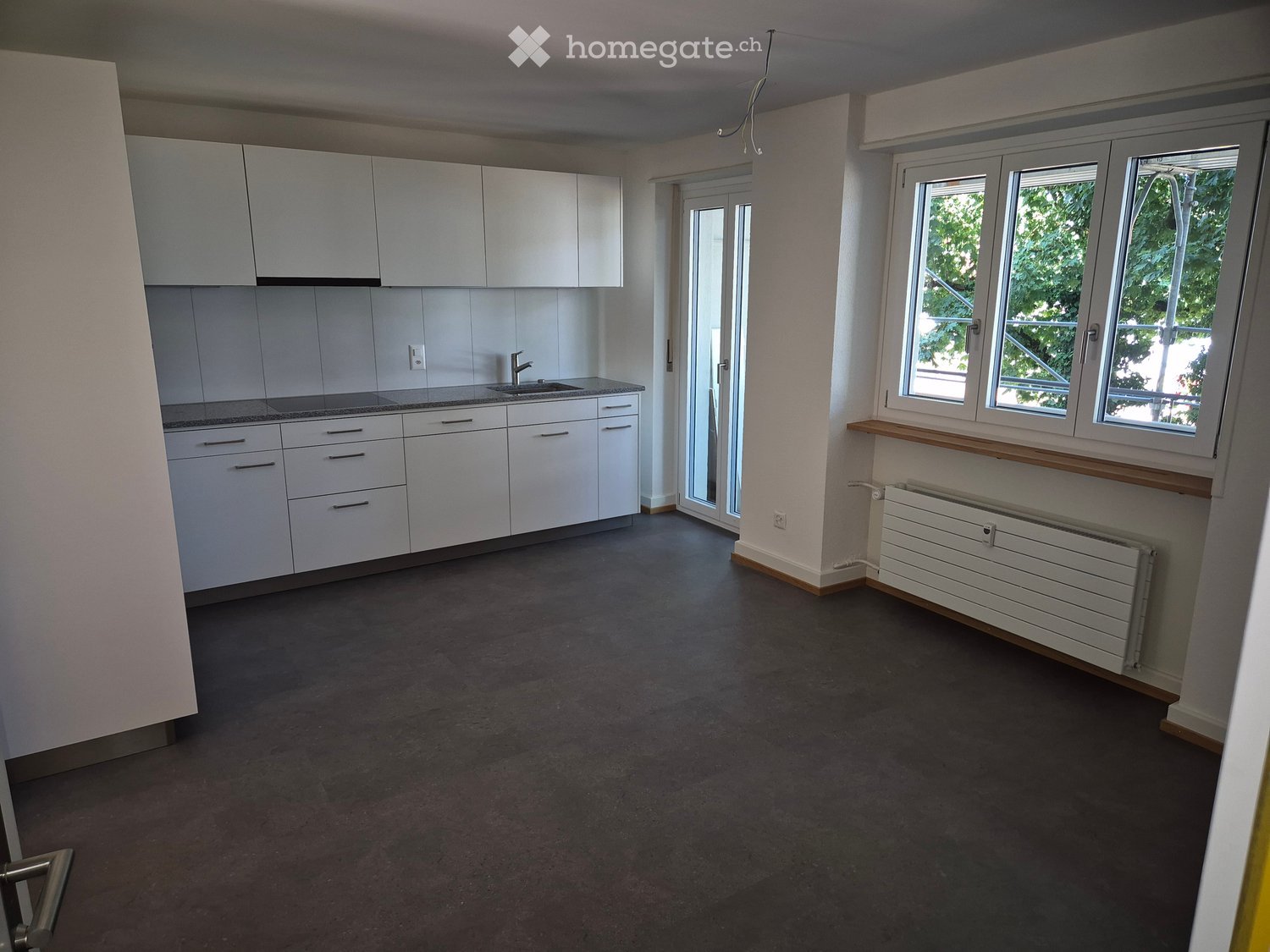 Empty room with white cabinets, sink, and windows. No furniture or appliances present.