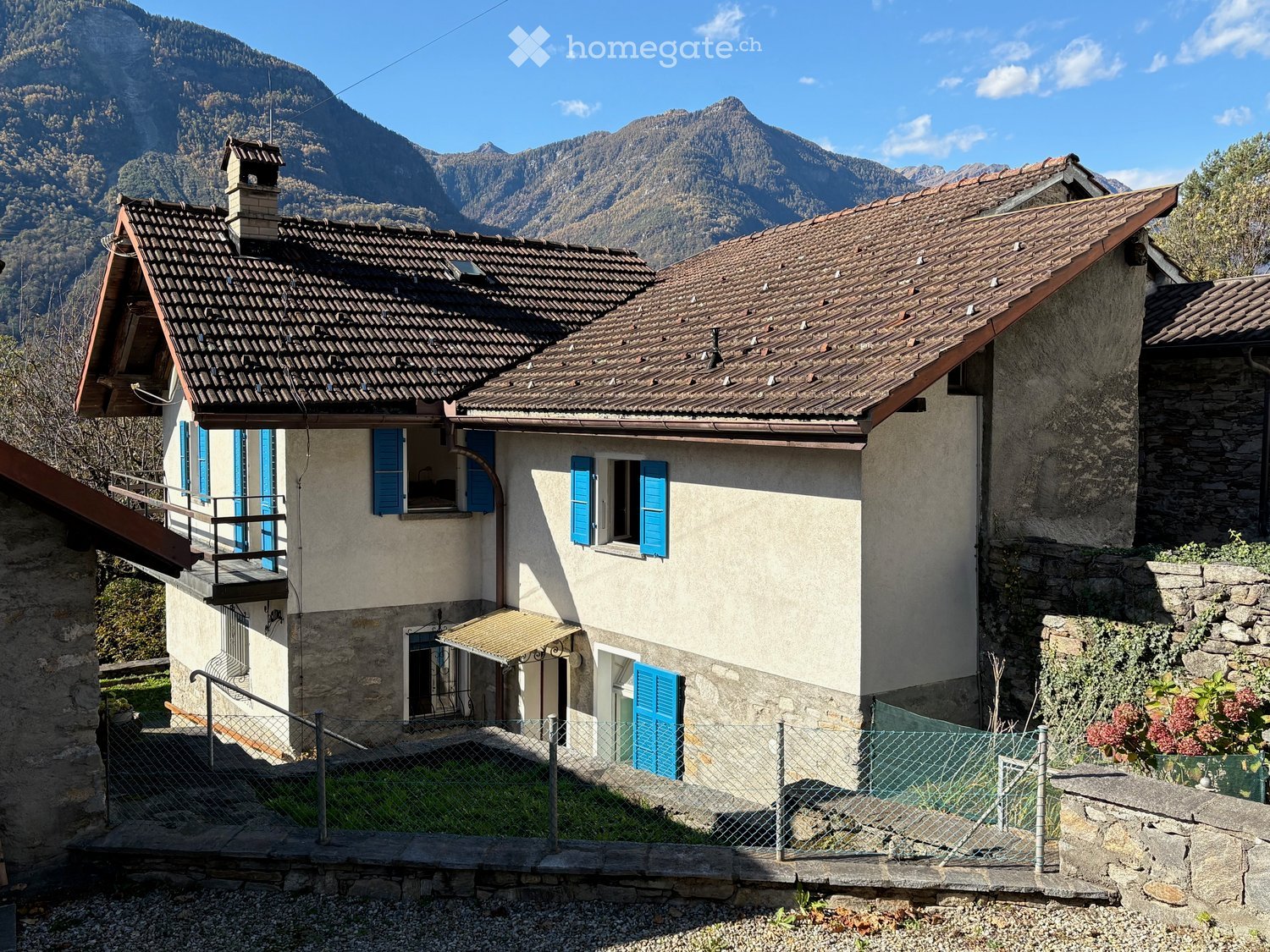 House with two stories, brown roof, blue shutters, small front balcony