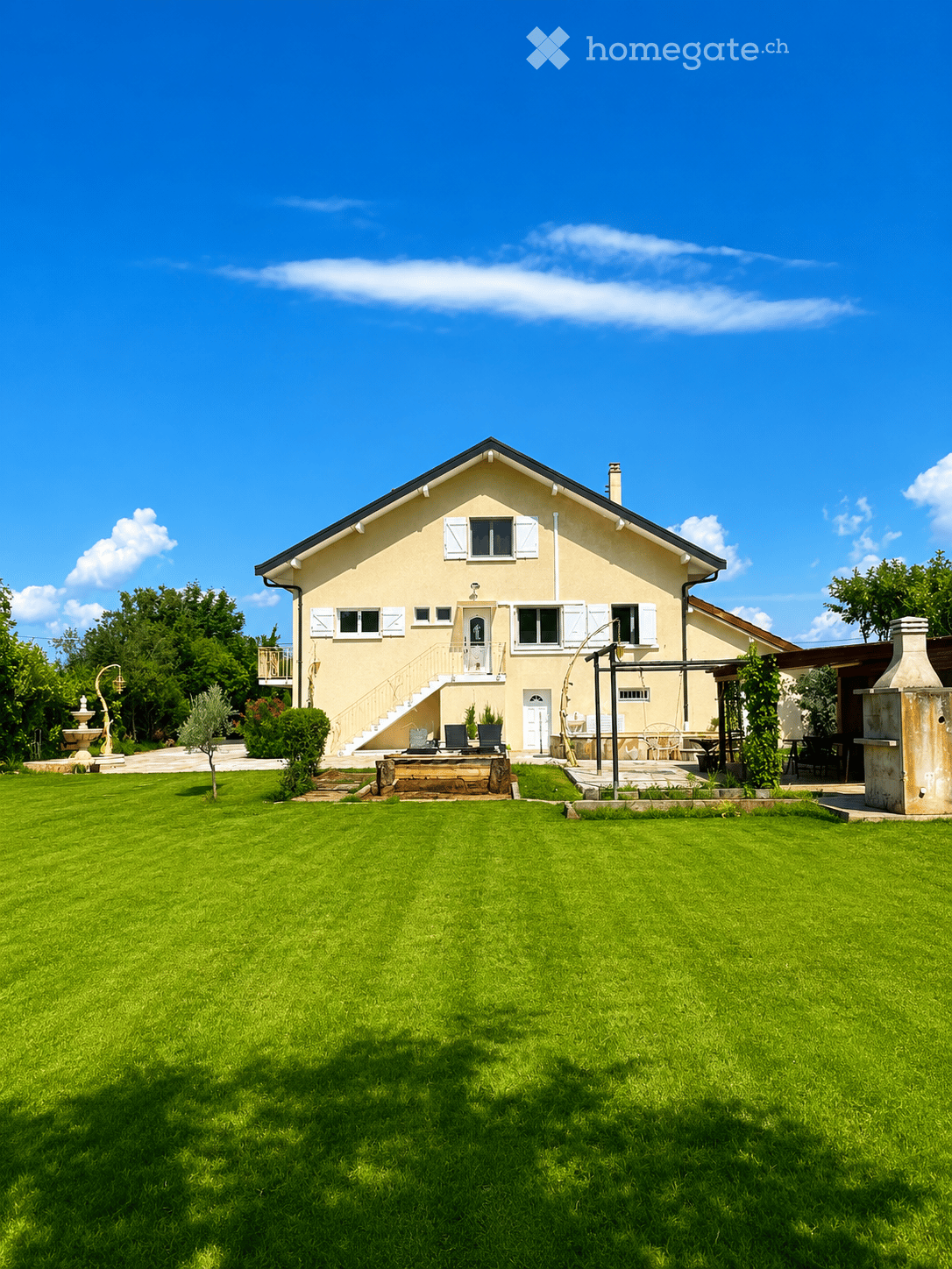 Two-story house with light yellow walls, white shutters, and a well-maintained lawn in front.