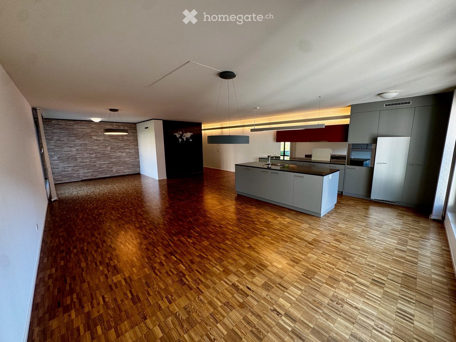 Modern kitchen with grey cabinets, a central island, and wooden flooring.