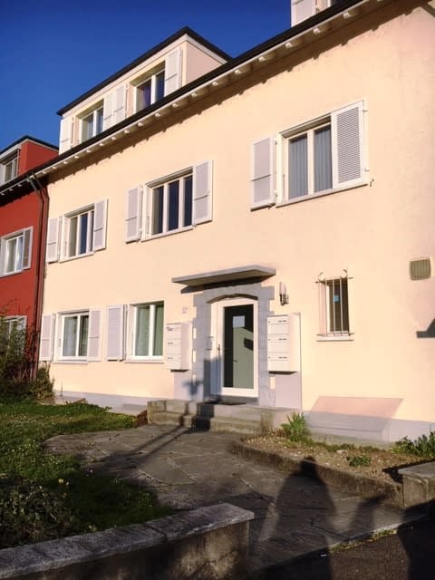Two story apartment building, pink and red paint, white windows, outdoor mailbox