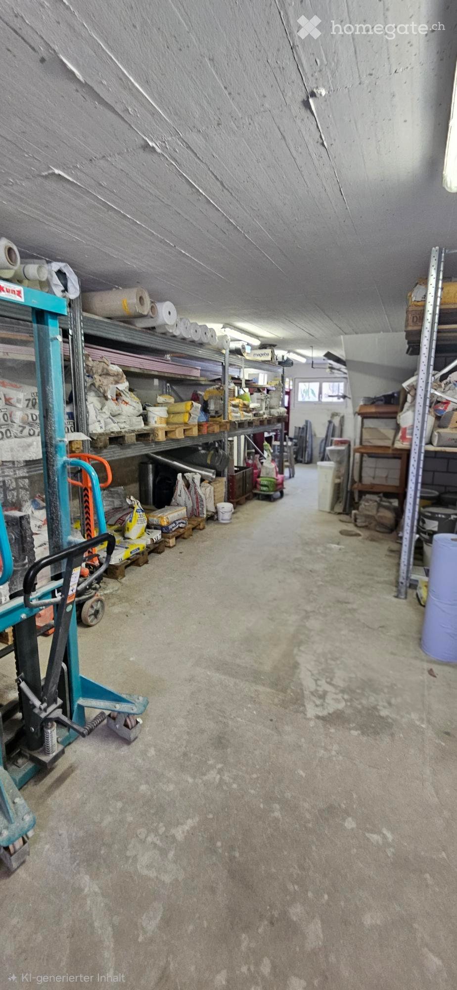 A spacious, unfinished storage area with concrete floors, metal shelving units, and various construction materials and tools stored on pallets and shelves.