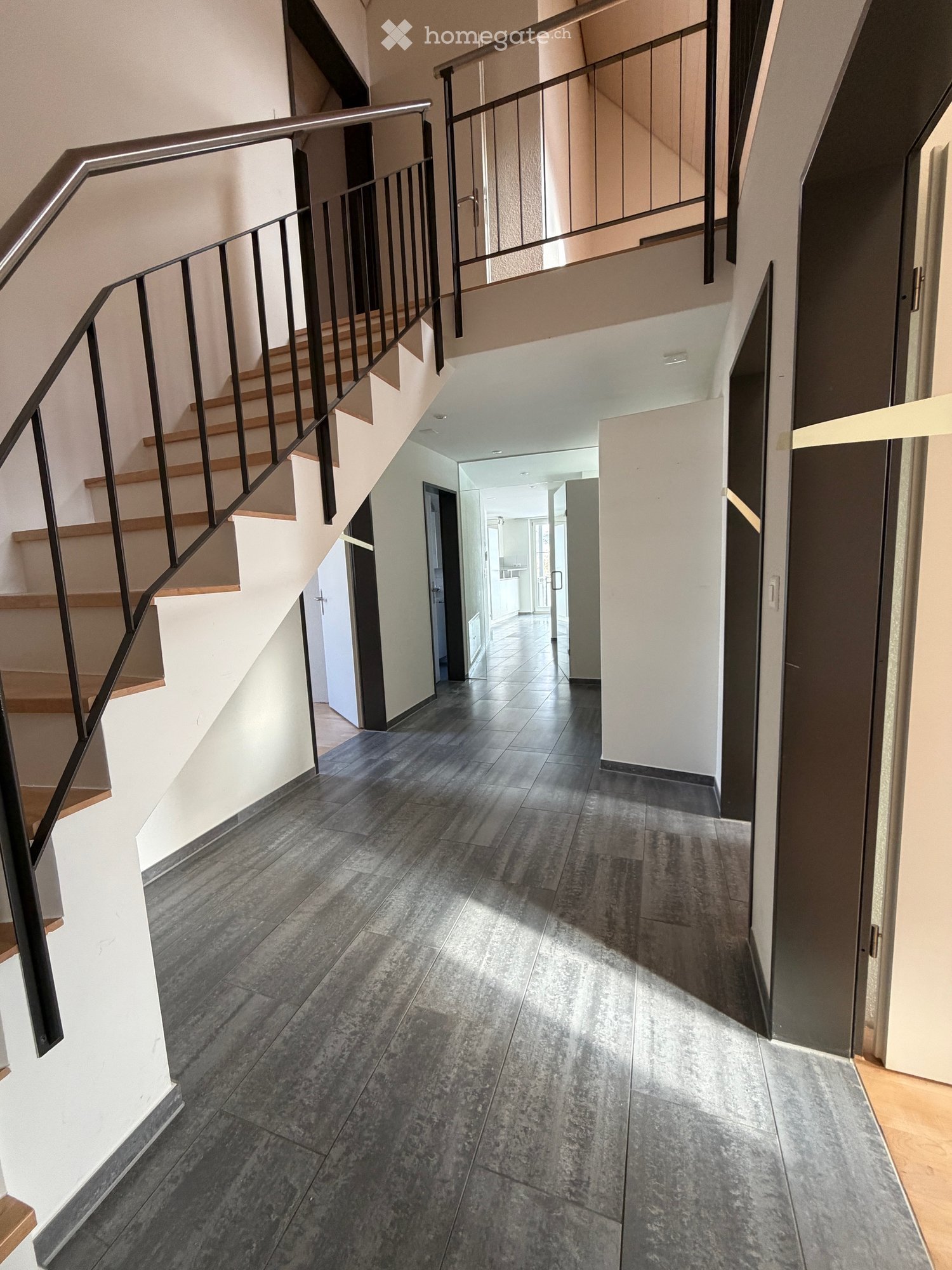 dark wooden flooring, white walls, open staircase, metal railings, empty hallway