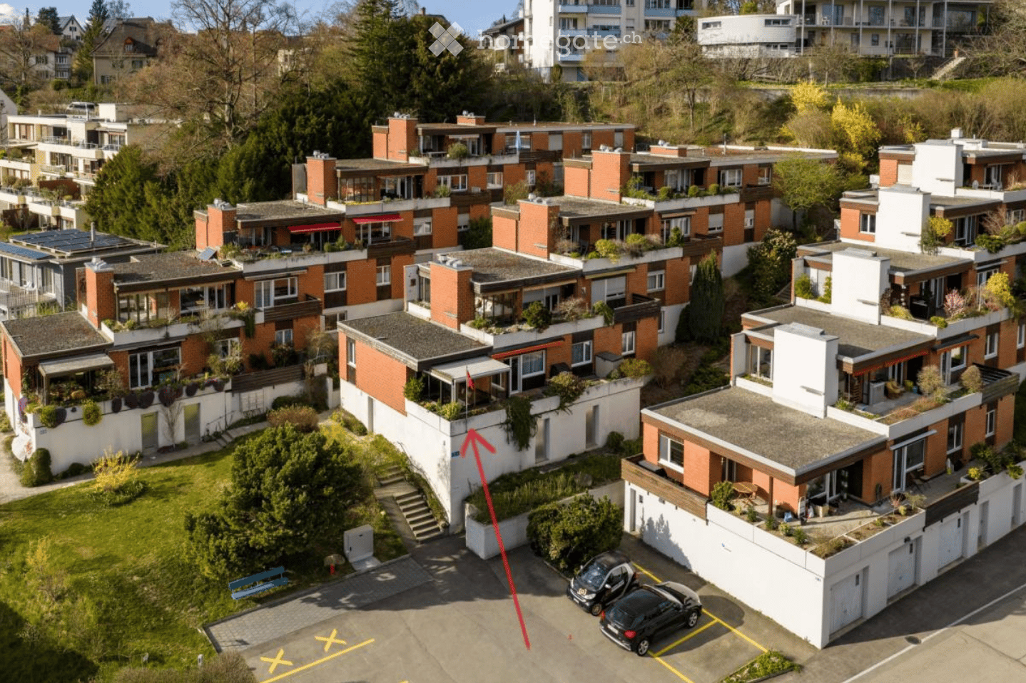 Aerial view of a residential complex with multiple buildings, green spaces, and parking areas.