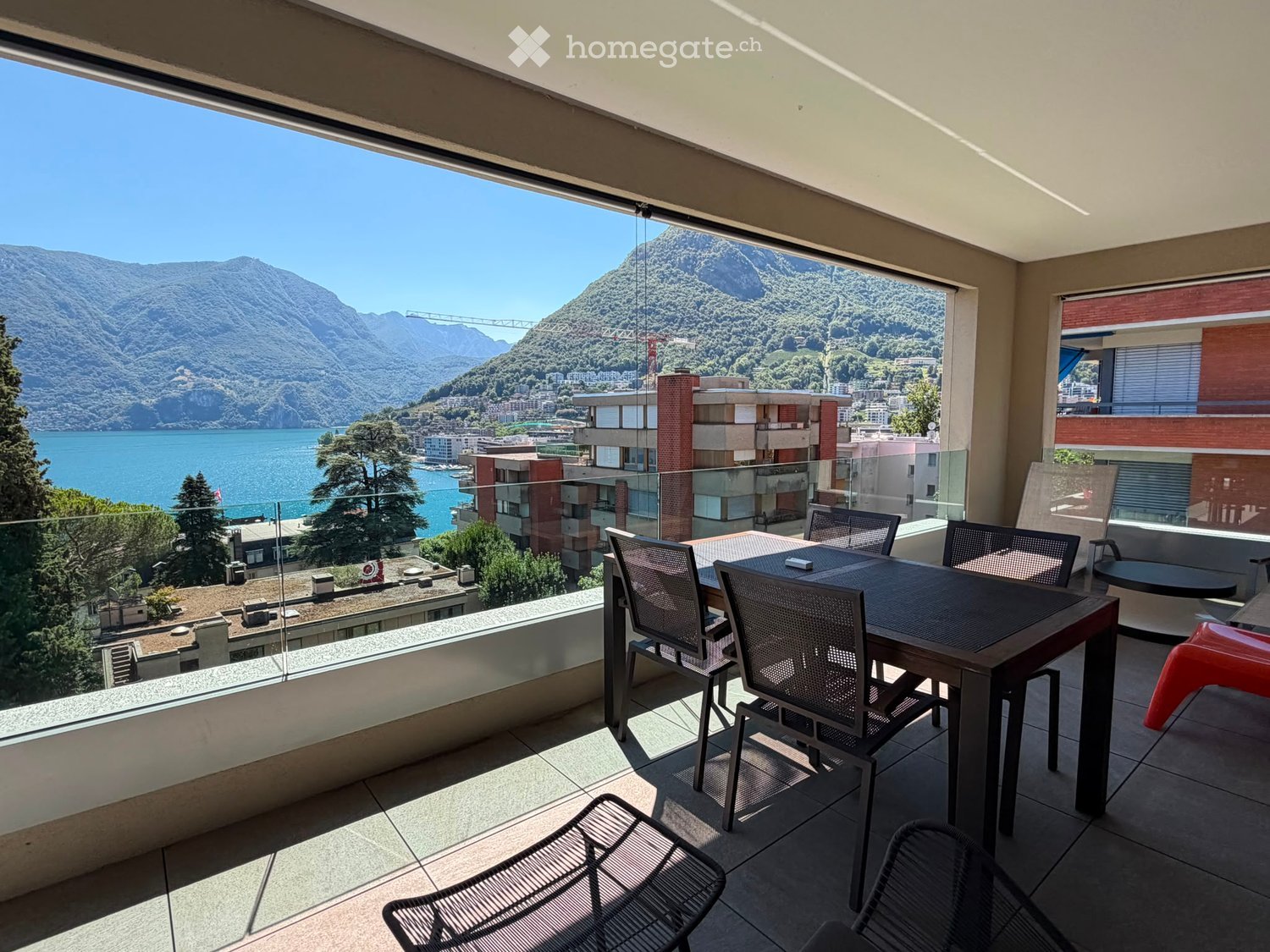 Balcony with a scenic view of a lake and mountains, furnished with a table and chairs.