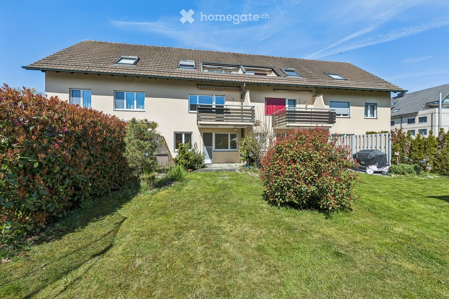 2 story house, beige exterior, brown roof, multiple windows, 2 balconies, well-maintained garden
