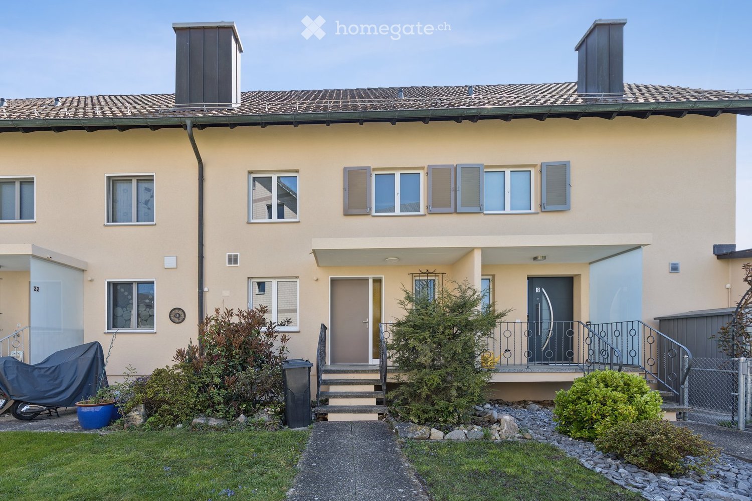 2-story house, beige exterior, tiled roof, 2 entrances, small front garden, covered walkway