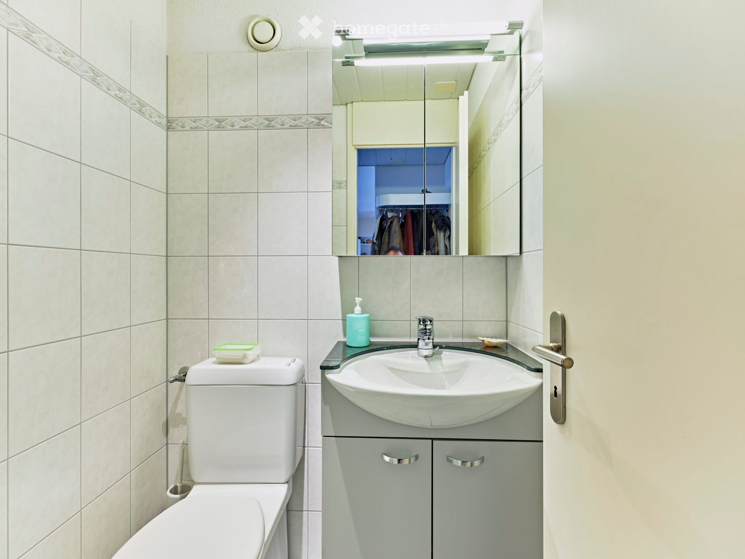 white tiles, modern fixtures, sink, toilet, mirror, small vanity