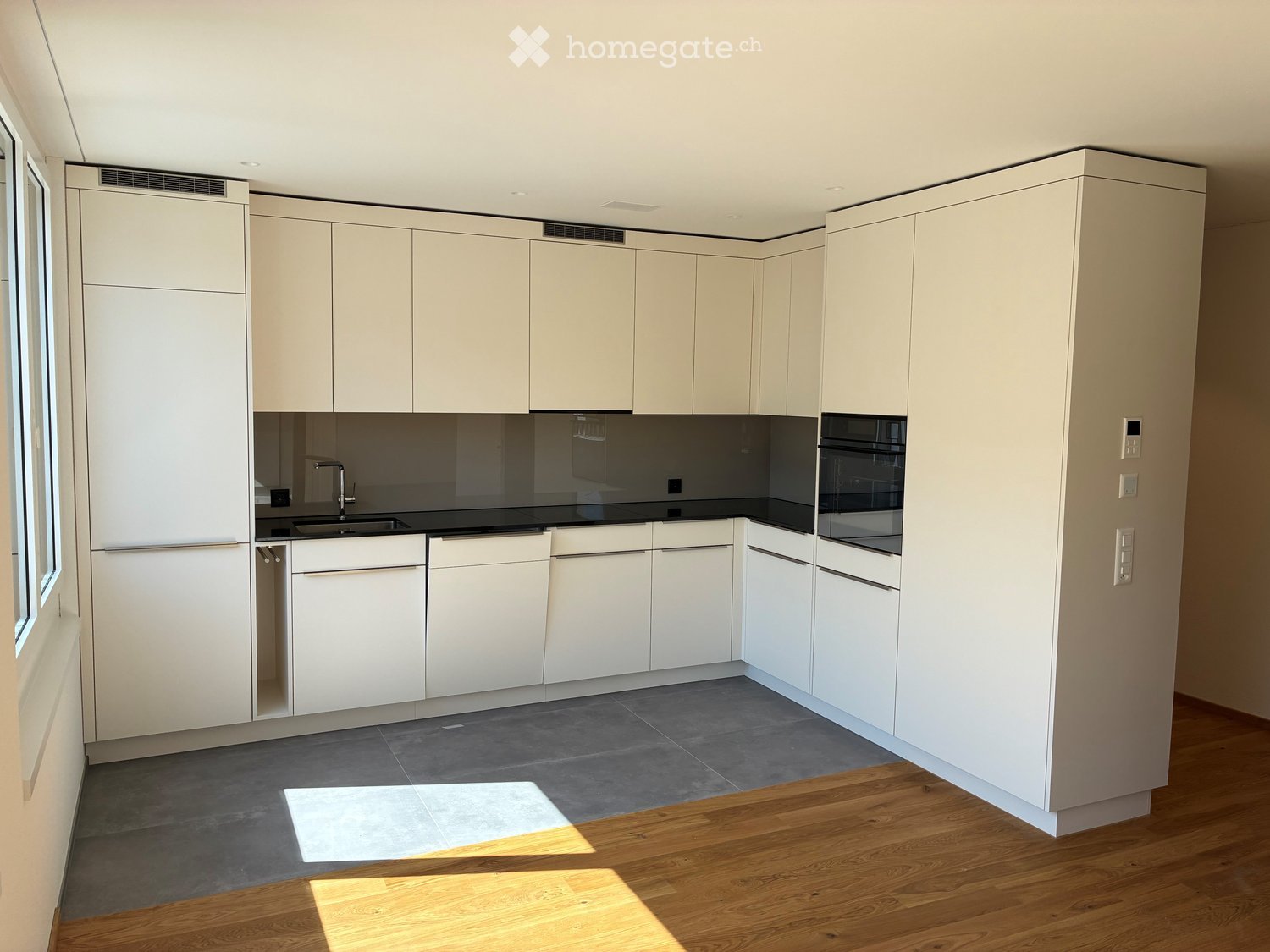 Modern kitchen with white cabinets, black countertops, and stainless steel appliances. Features a sink, faucet, and oven.