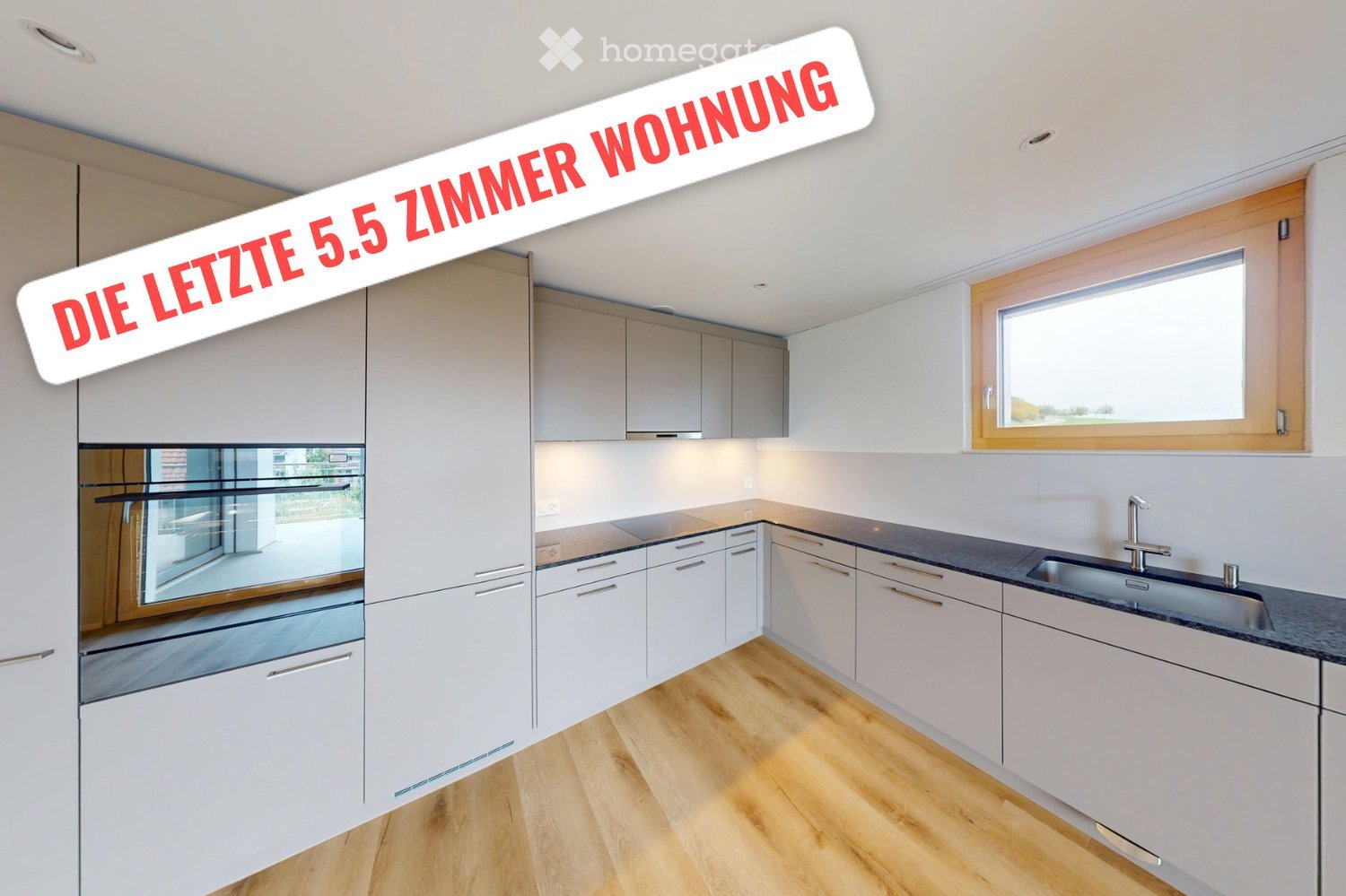 Modern kitchen with white cabinets, wooden flooring, and stainless steel appliances including an oven and sink.