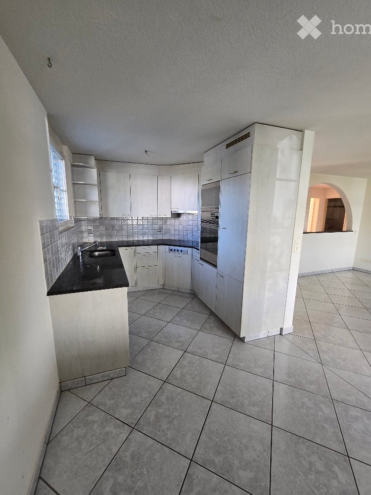 Modern kitchen with white cabinets, black countertops, tiled backsplash, and stainless steel appliances including a sink, oven, and dishwasher.