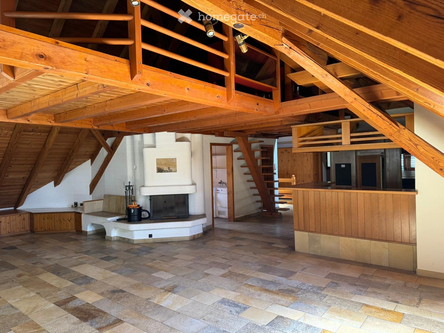 Spacious living area with exposed wooden beams, fireplace, sofa, and bar counter.