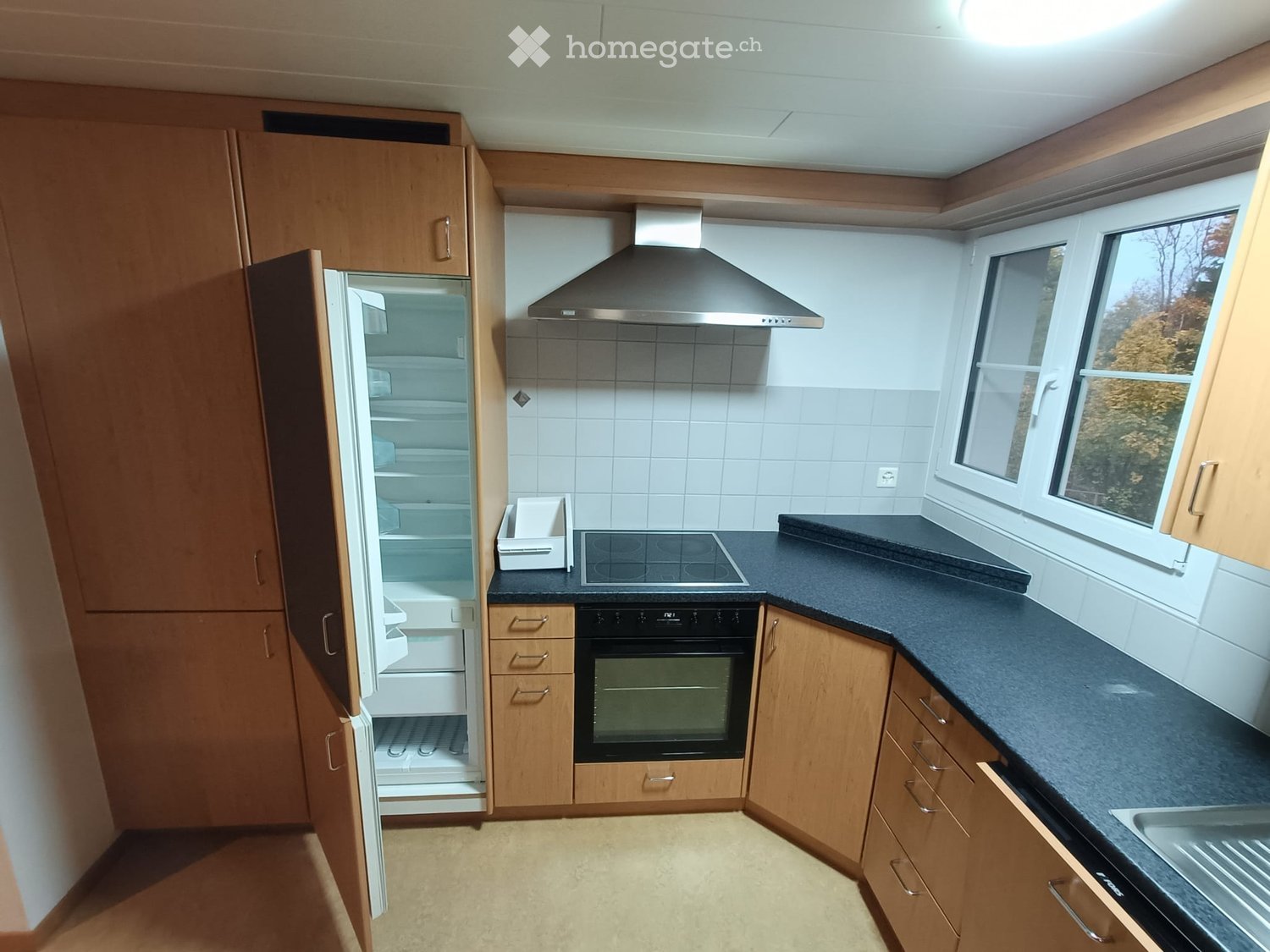 kitchen with wooden cabinets, modern appliances, black granite countertops, open refrigerator, built-in oven and stove