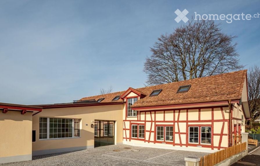 2-storey house with brick walls, brown roof, red trims, large windows, and a driveway