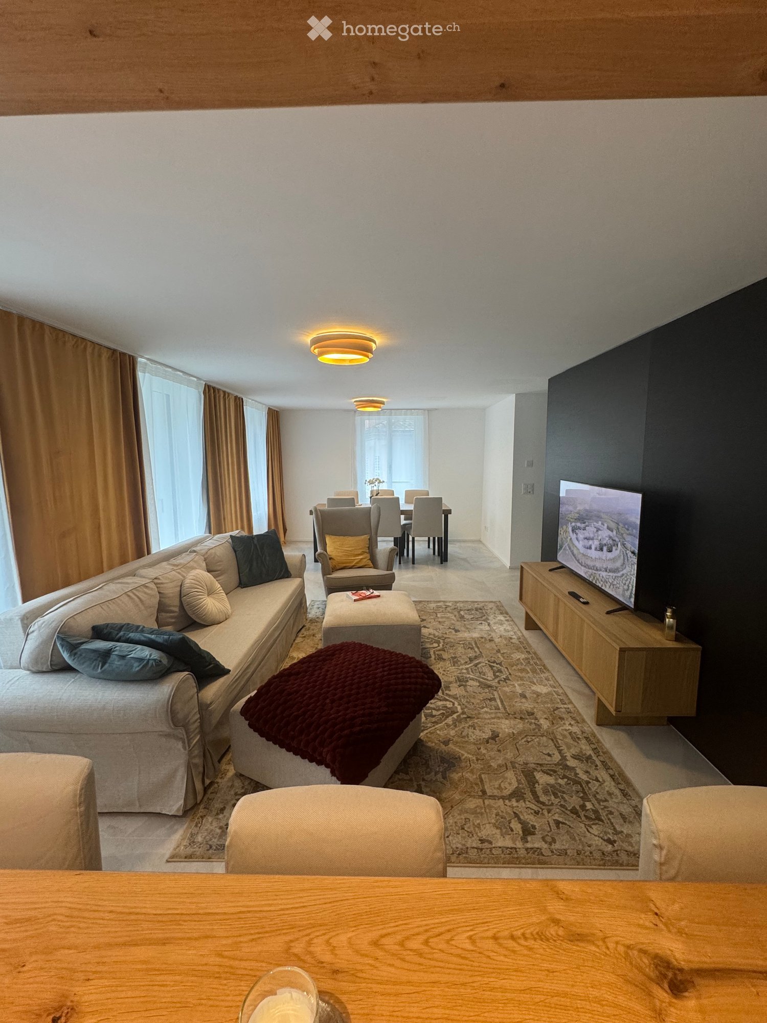 large living room with sofa, coffee table, TV, rug, dining table, chairs, and a view of a dining area