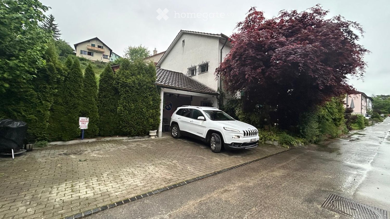 Two-story house with a garage, white SUV parked inside, surrounded by greenery and trees.
