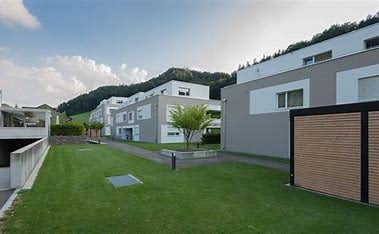 modern apartment buildings, green lawn, trees, mountains in the background