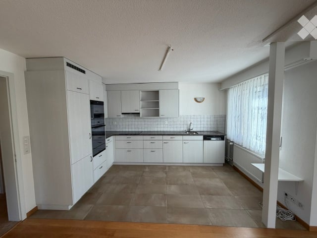 Bright, modern kitchen with white cabinets, stainless steel appliances, and a tiled floor. Features include a sink, oven, dishwasher, and radiator.