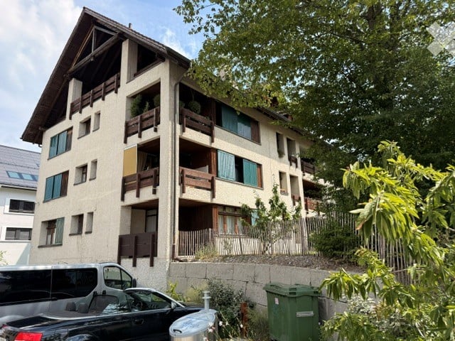 Multi-story residential building with balconies, large windows, and a mix of modern and traditional architectural elements.