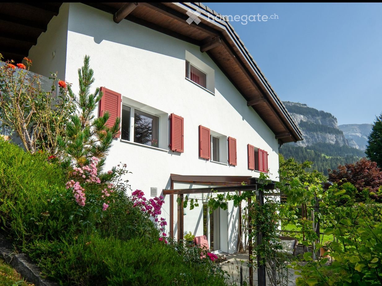 white house, red shutters, small garden, balcony, green plants, pink flowers
