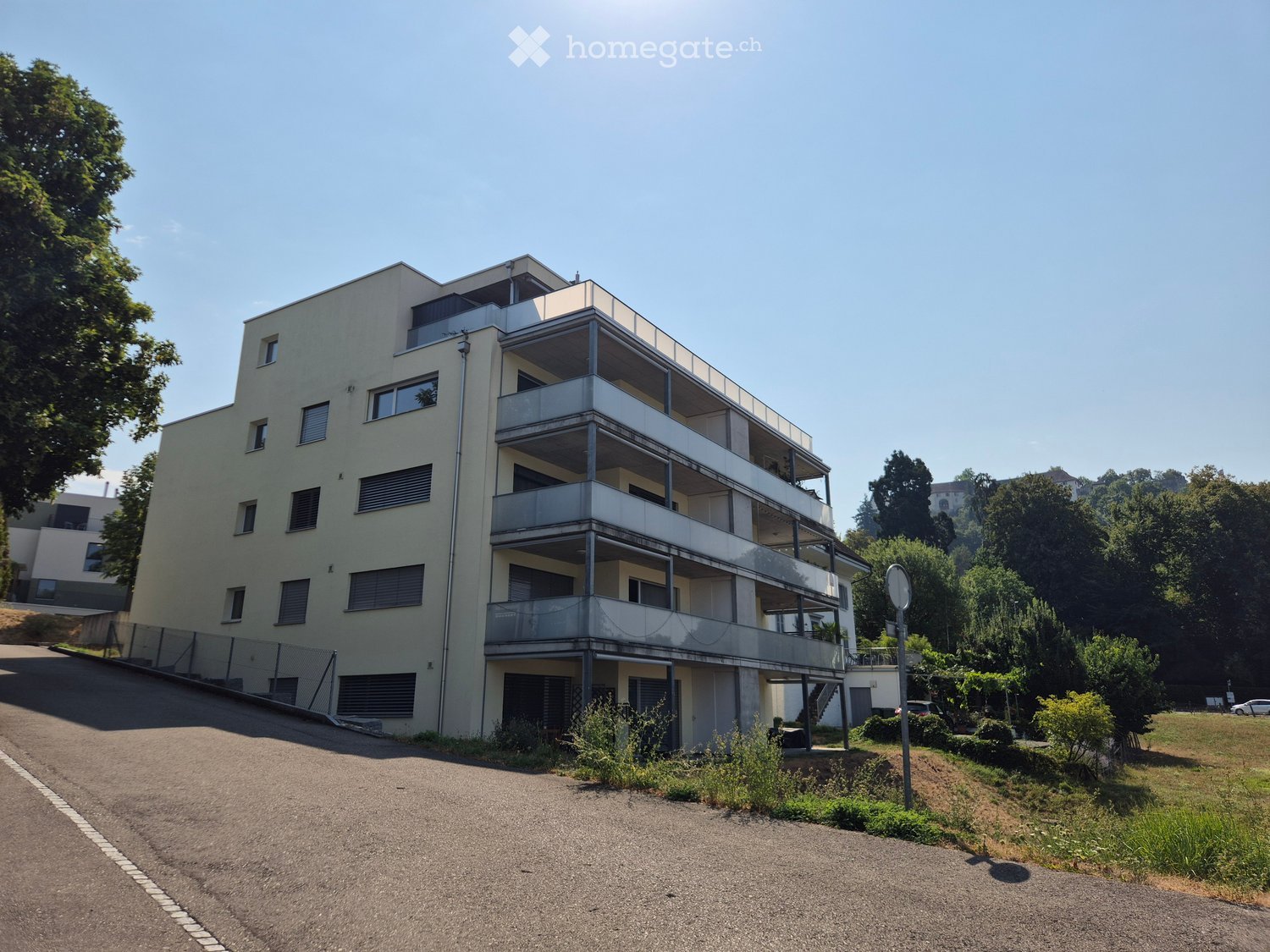Modern multi-story residential building with balconies, large windows, and a clean facade.
