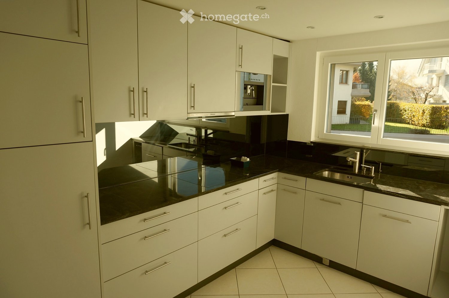 Modern kitchen with white cabinets, black countertops, and stainless steel sink.