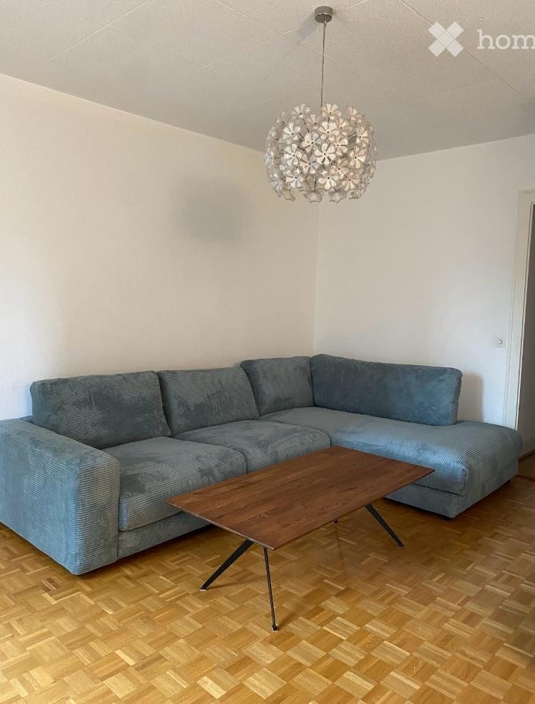Modern living room with a grey sectional sofa, a wooden coffee table, and a decorative pendant light hanging from the ceiling.