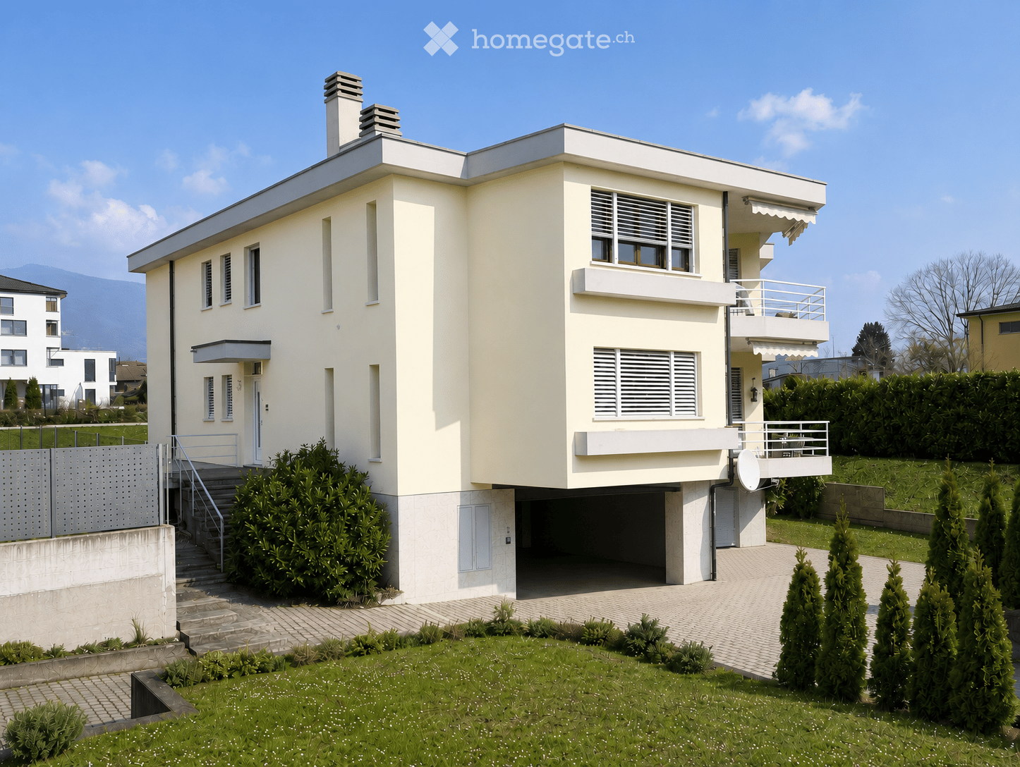 Modern two-story house with white exterior, flat roof, garage, and balcony on the upper level.