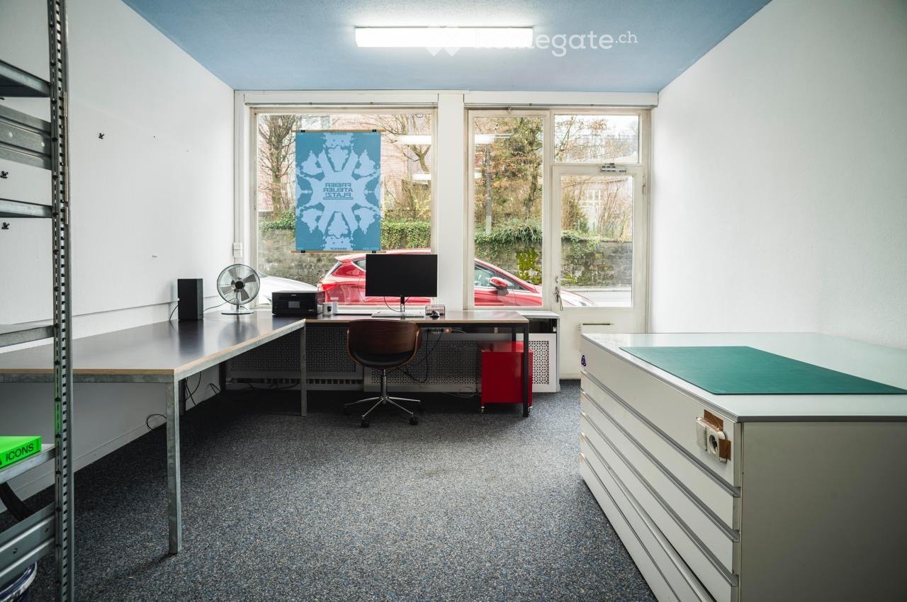 Office space with a desk, chair, computer monitor, fan, speaker, printer, and storage cabinets.