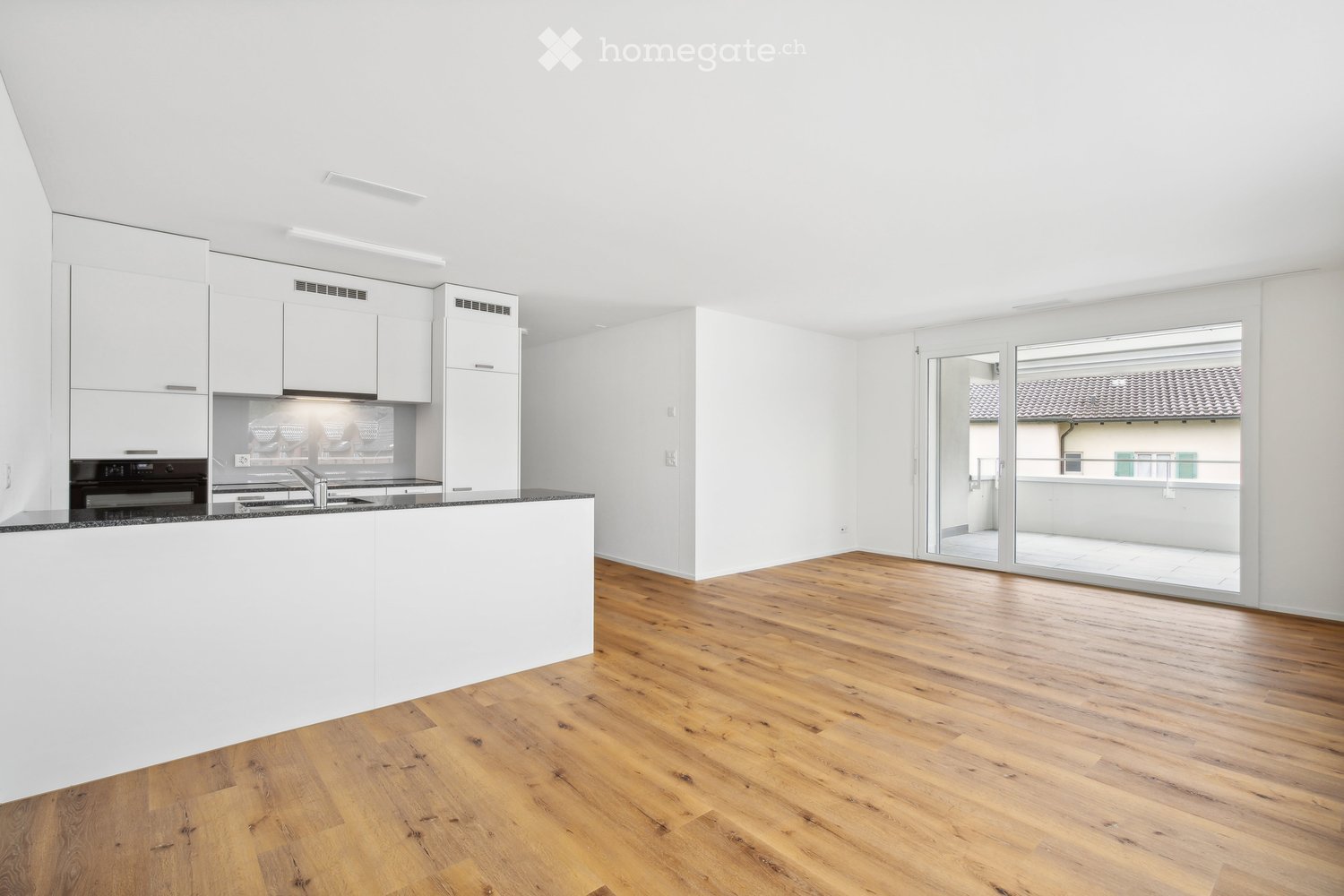 modern kitchen, white cabinets, wooden floor, sink, black countertop, sliding glass doors to balcony