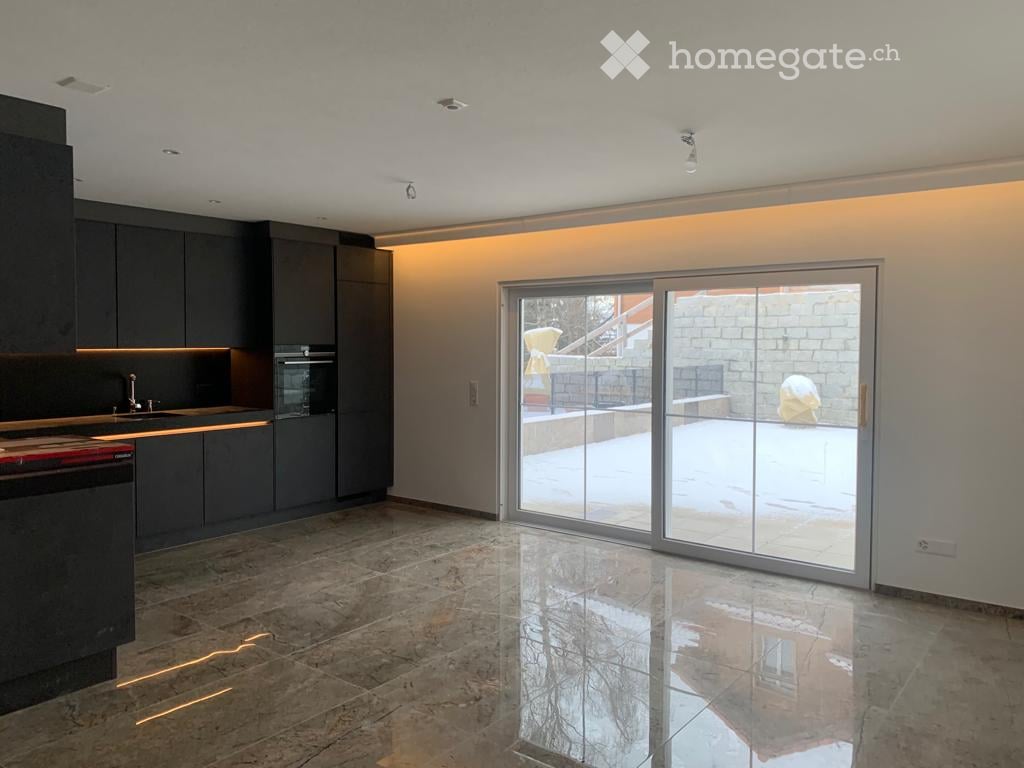 Modern kitchen with dark grey cabinets, a large sliding glass door leading to a snowy outdoor area, and a polished tile floor.