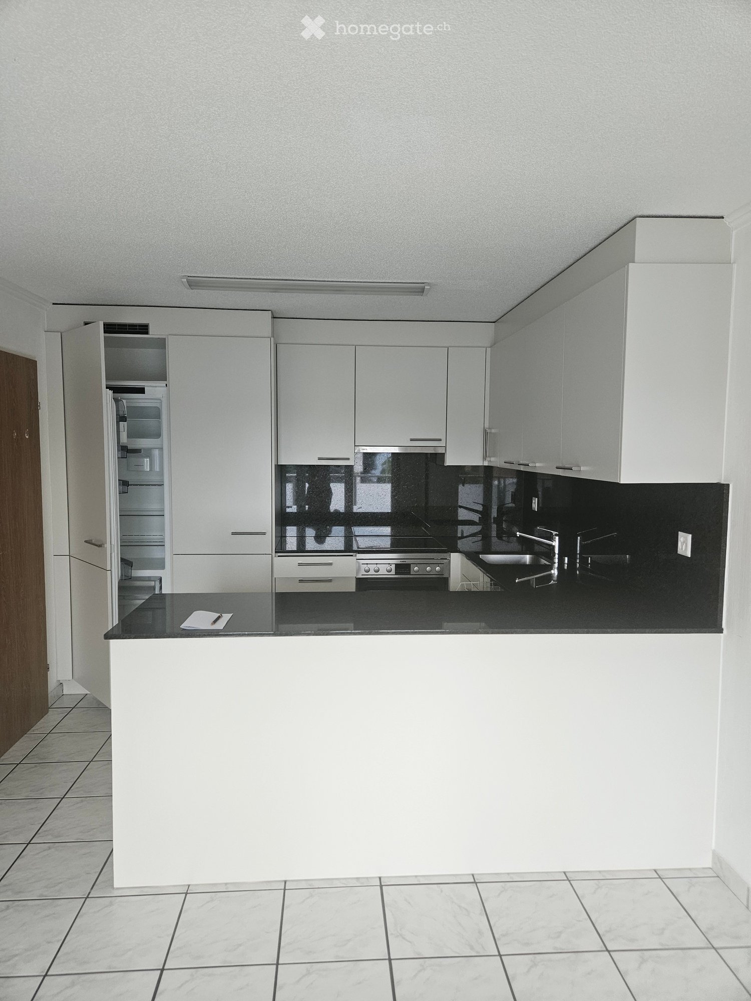 Modern kitchen with white cabinets, black countertops, stainless steel appliances, and a central island.