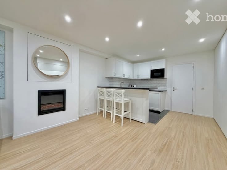 Modern kitchen with white cabinets, a central island with bar stools, a built-in microwave, and a fireplace on one wall.