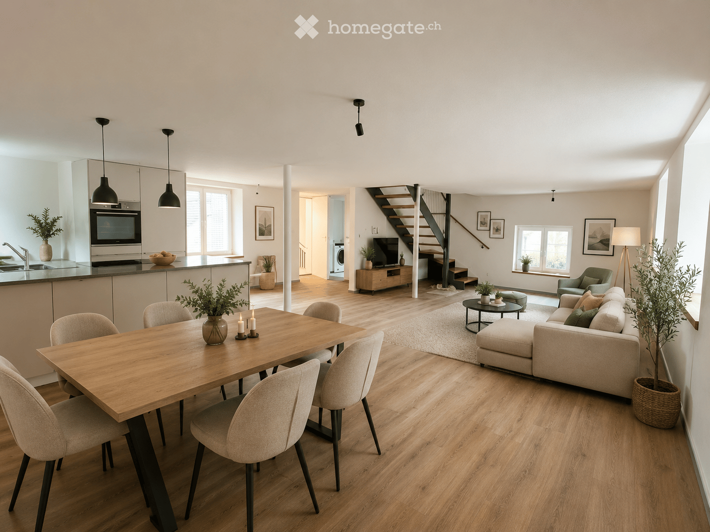 Open-plan living and dining area with light wood flooring, a modern sofa, coffee table, dining table with chairs, kitchen island, and pendant lights.