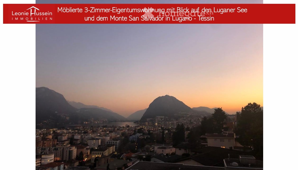 Panoramic view of Lugano Lake and Monte San Salvador at sunset, with cityscape and surrounding mountains visible.
