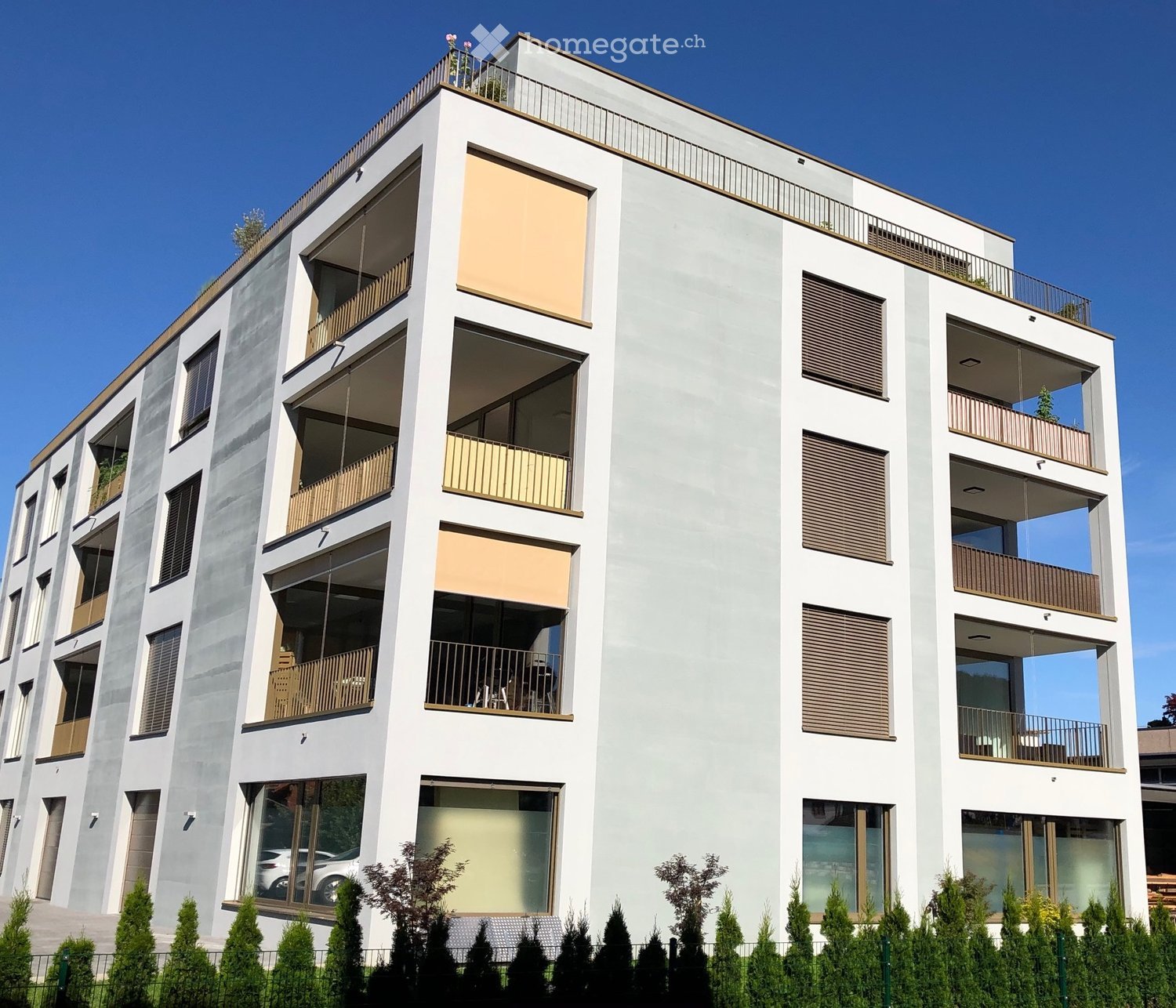 Modern multi-story residential building with balconies, large windows, and contemporary design.