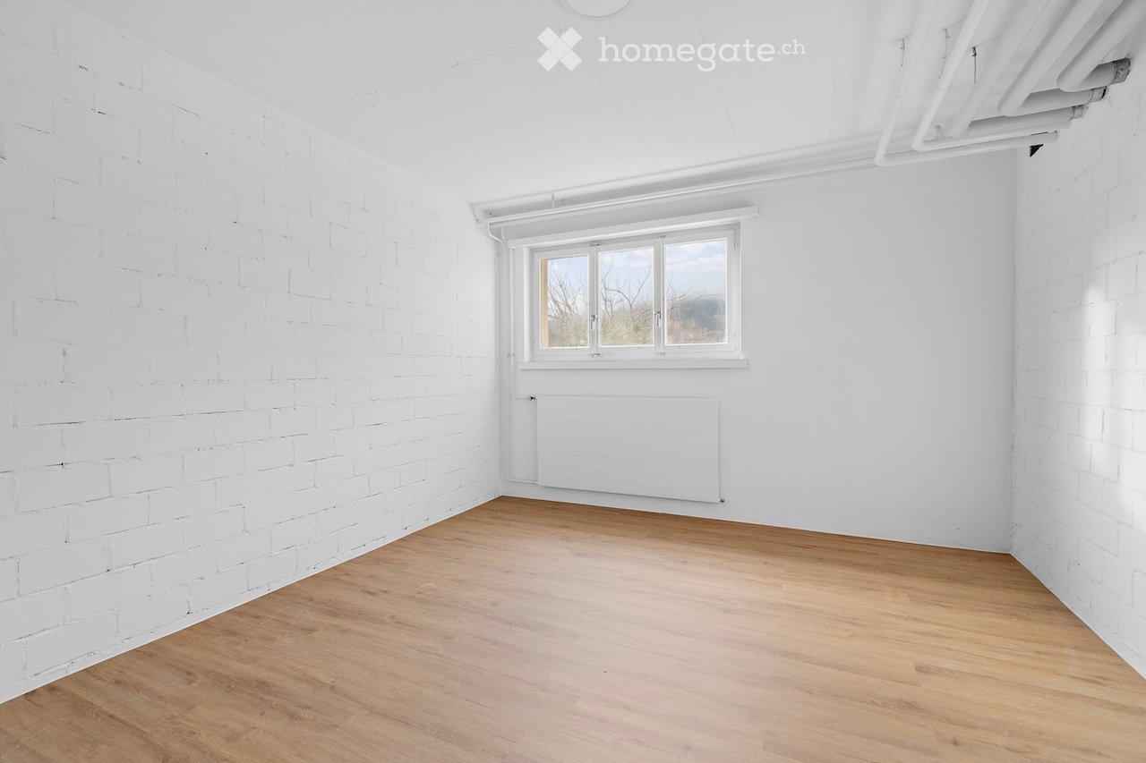 empty room with white brick walls, wooden floor, radiator, window