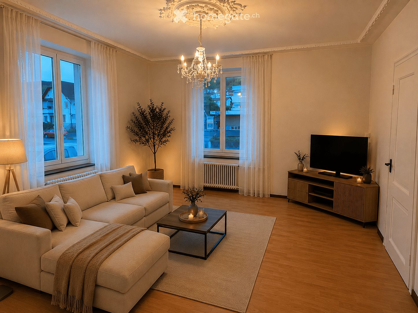 Modern living room with a beige sectional sofa, coffee table, TV stand, chandelier, and decorative plants.