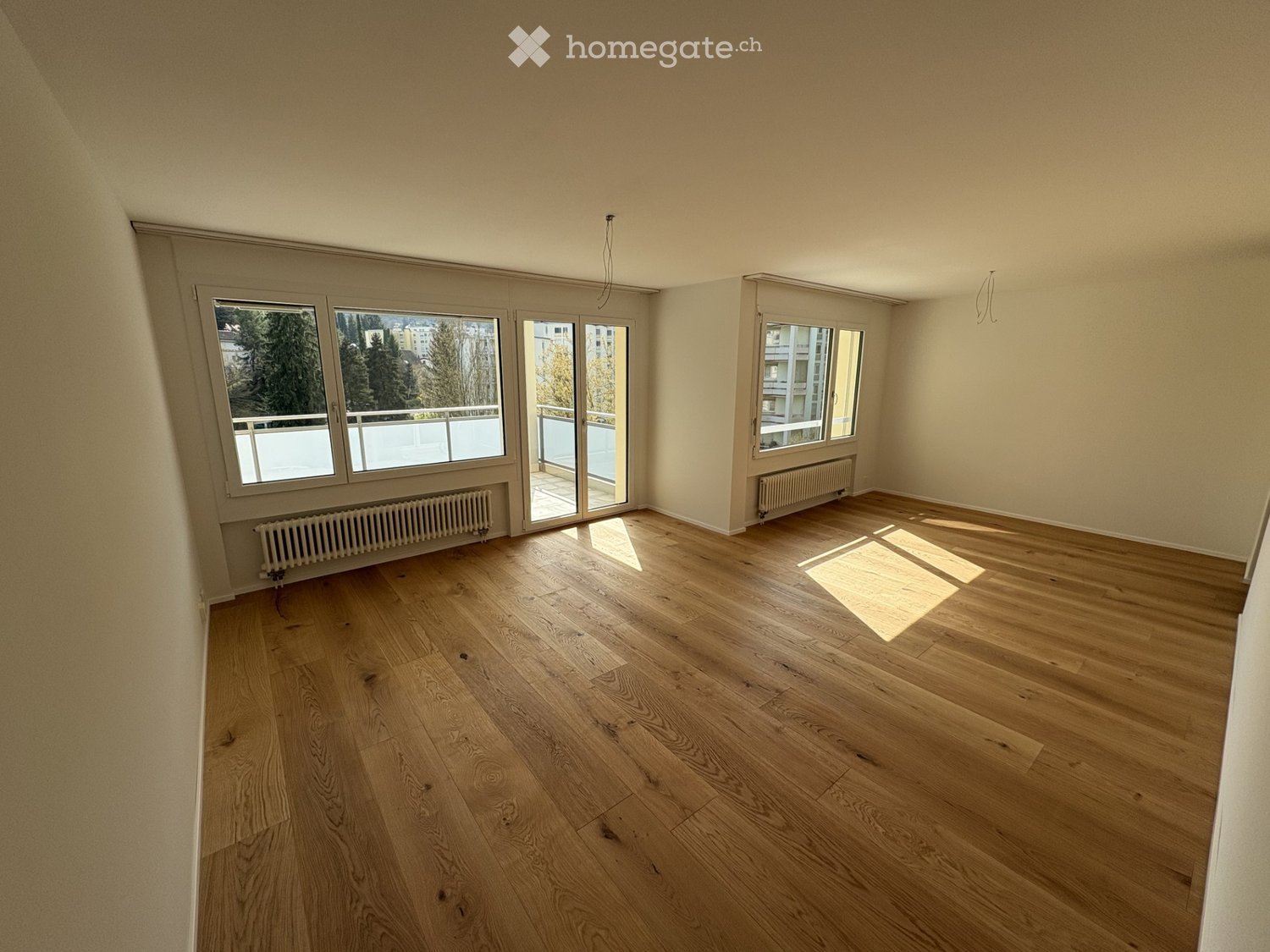 empty room, wooden floor, white walls, large windows, sliding glass doors to balcony